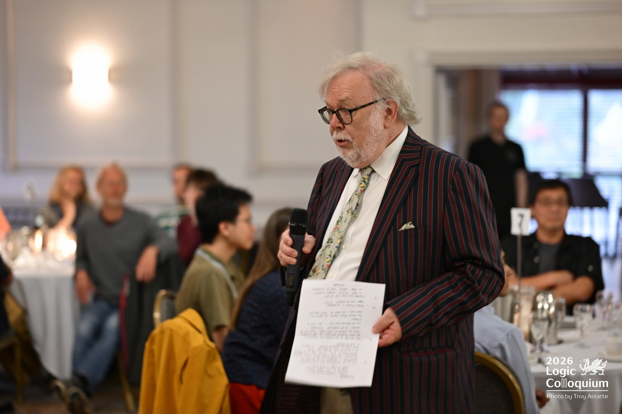 photograph of a distinguished professor walking about a dining room talking about logic and Wales.