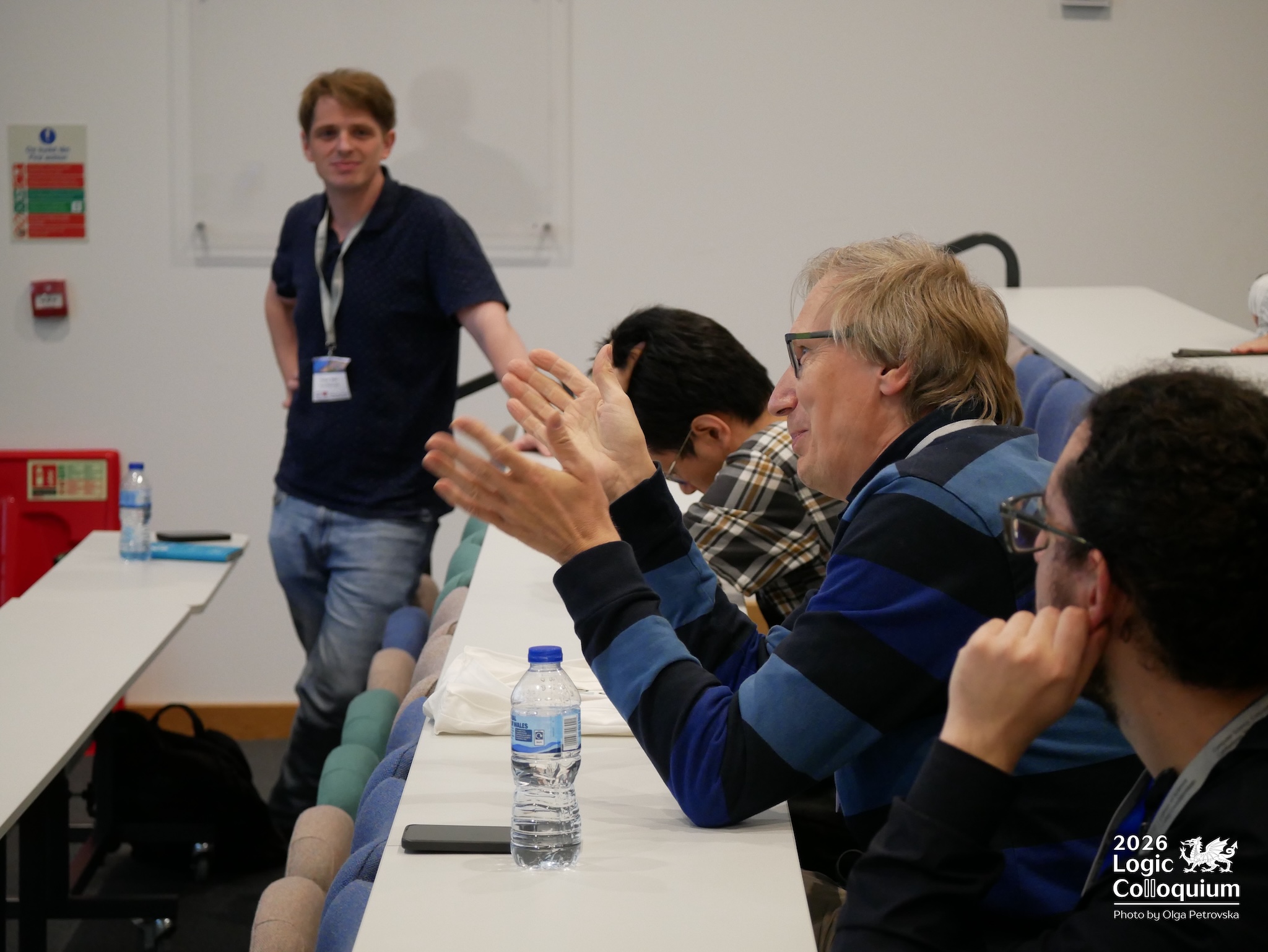 Photograph of an audience member with hands spread to help ask a question. The facial expression is positive.