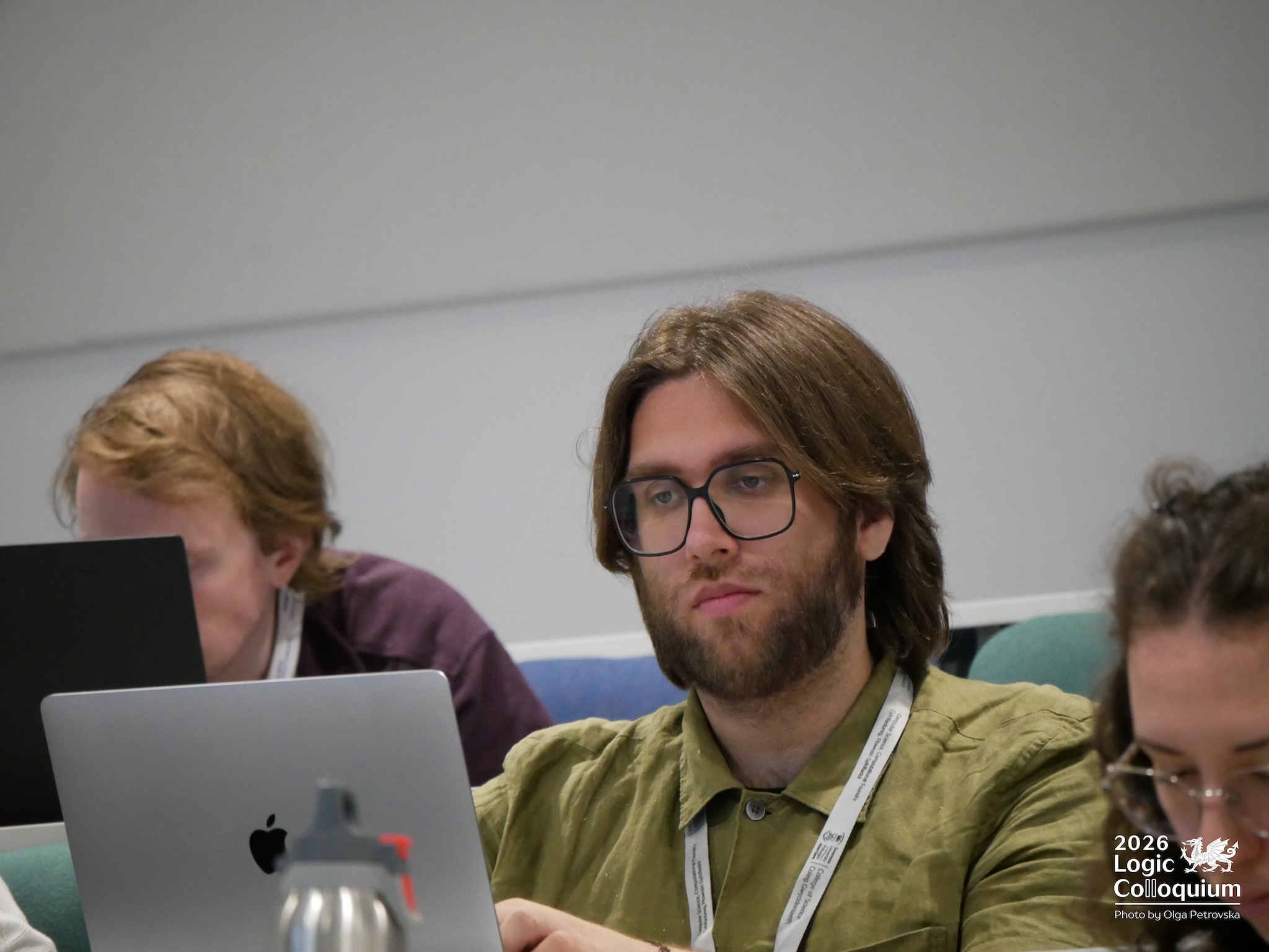 Photograph of an audience member looking perhaps at the speaker, perhaps at their laptop. In the background, someone undeniably looks at their laptop.