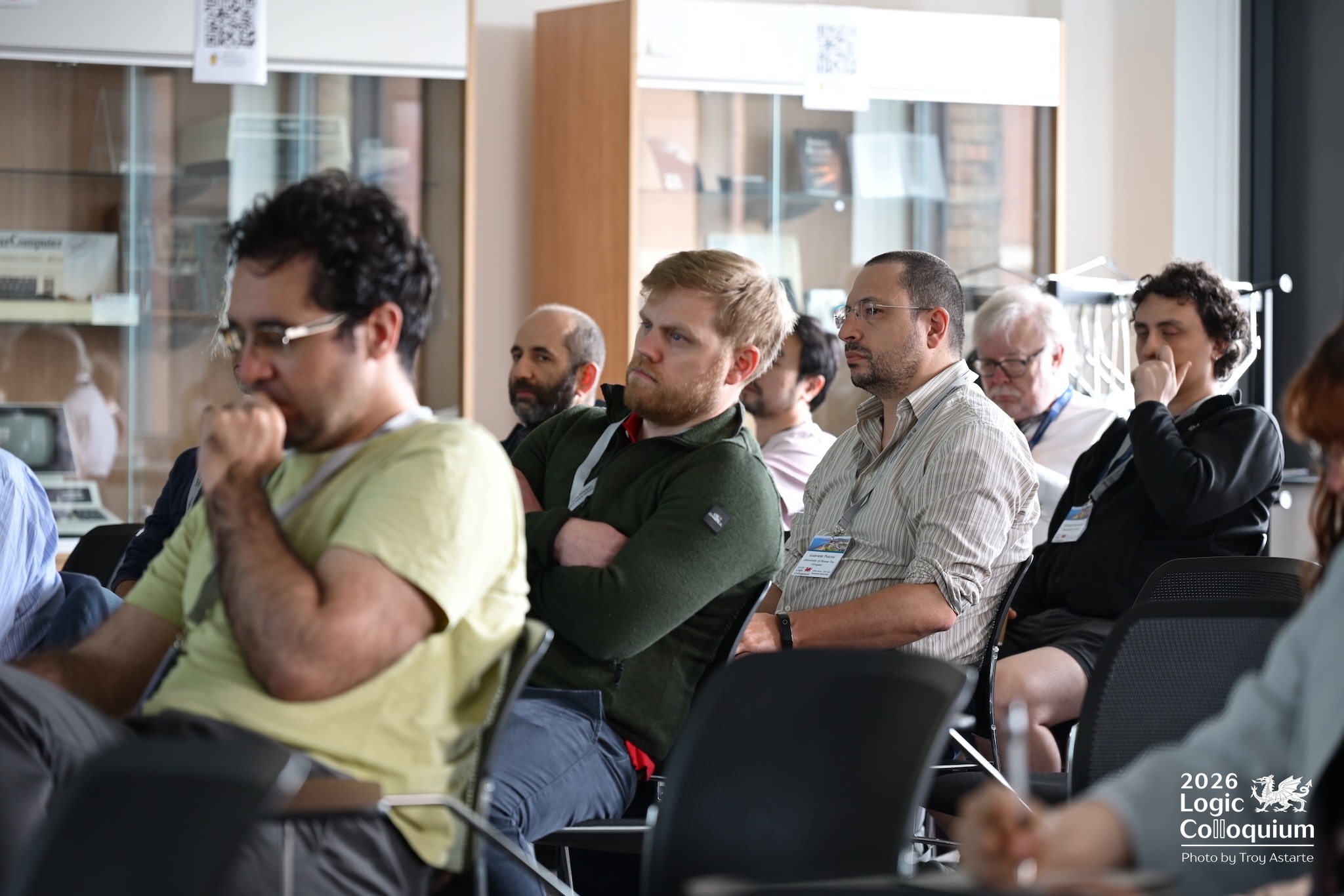 Photograph of audience carefully contemplating the speaker's points, with items from the History of Computing Collection behind.
