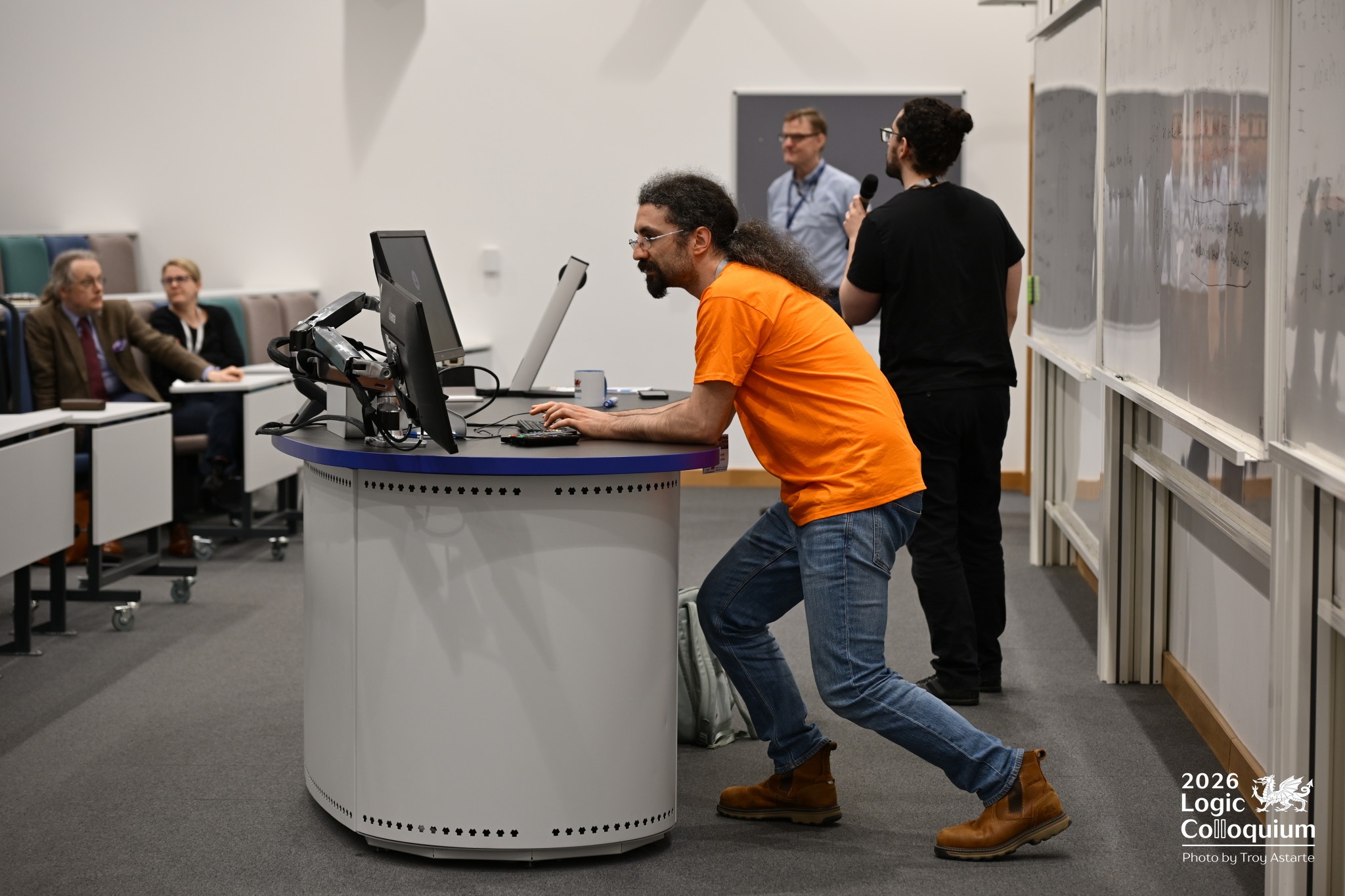 Photograph of an organiser wrestling with technology so hard that a special stance is needed.