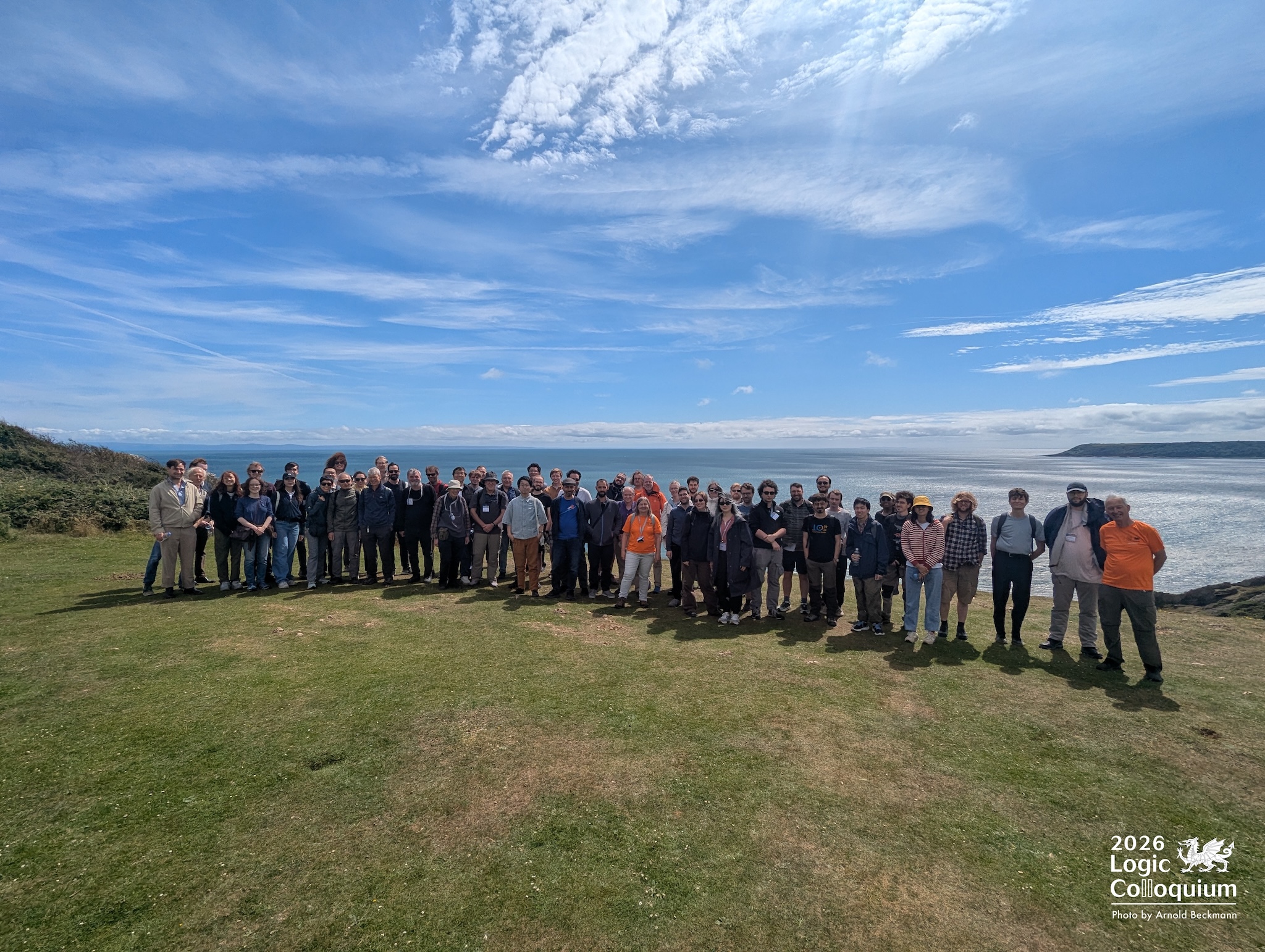 photograph of approximately fifty people standing on a grassy clifftop with the sea in the background.