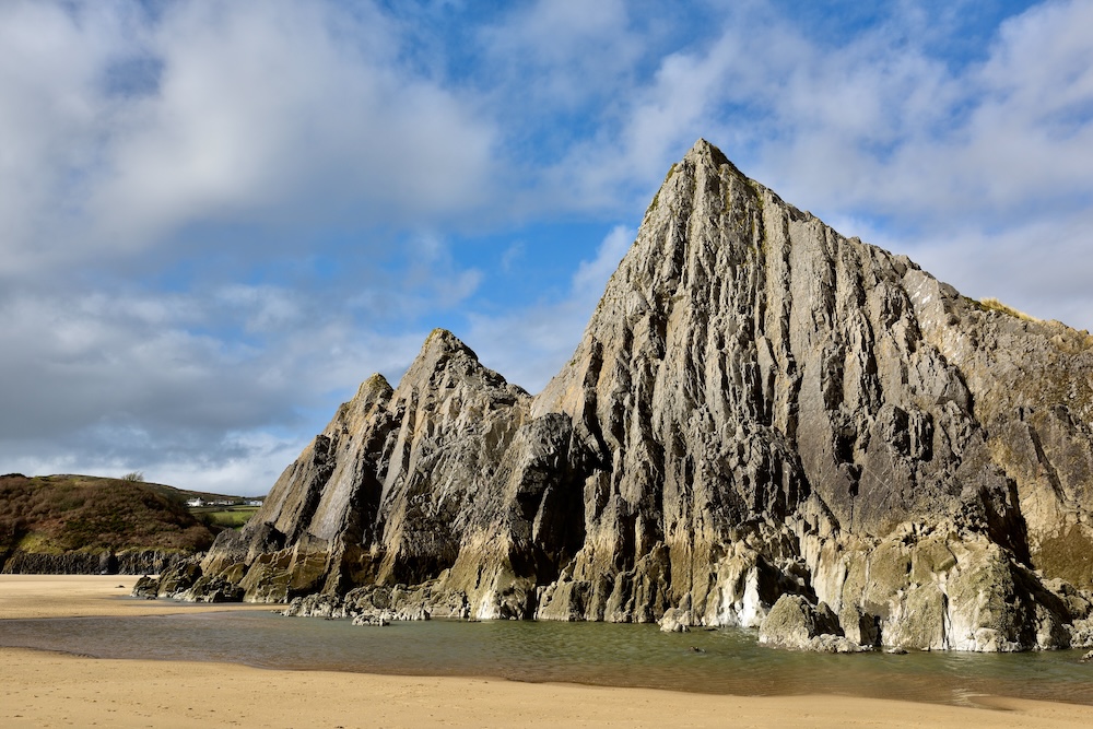 Photograph of three pointed cliffs on a beach.